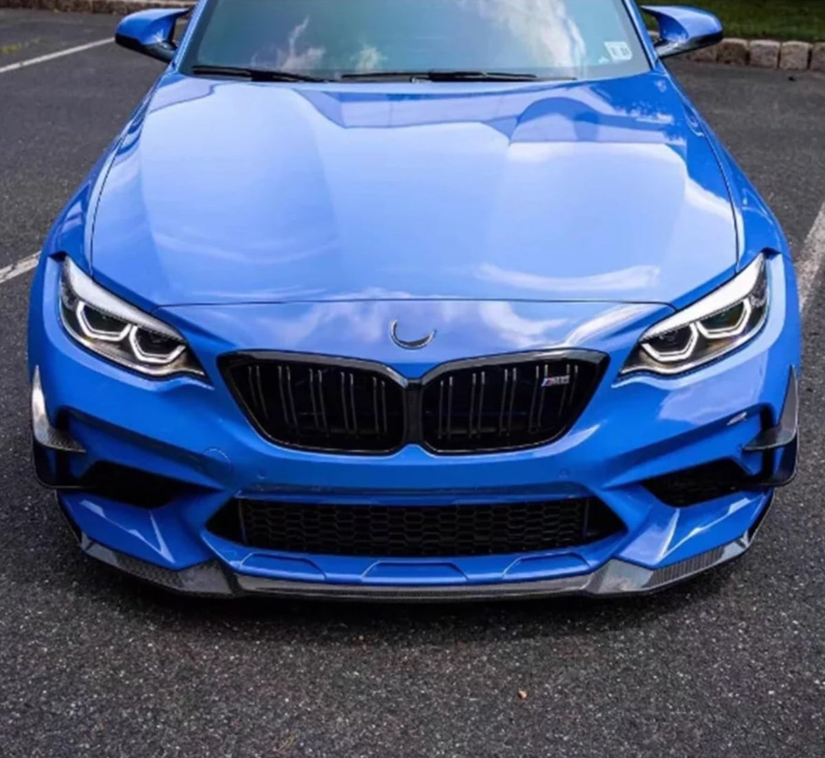 Front view of a blue BMW F87 M2 with carbon fiber front canards and carbon front lip