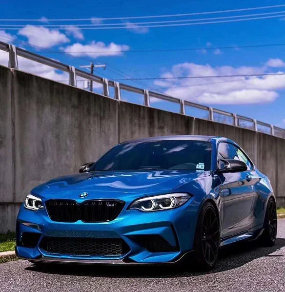 Kék BMW F87 M2 elölről ferdén, felszerelt MP Style carbon első koptatóval