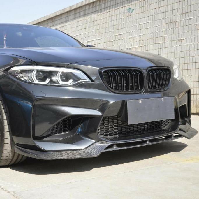 Sötétszürke BMW F87 M2 eleje ferdén, közelről, felszerelt V Style carbon első koptatóval