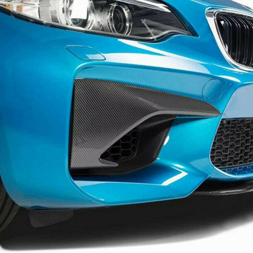 Kék BMW F87 M2 első lökhárítója közelről, a szélső légbeömlőknél carbon felső splitterekkel