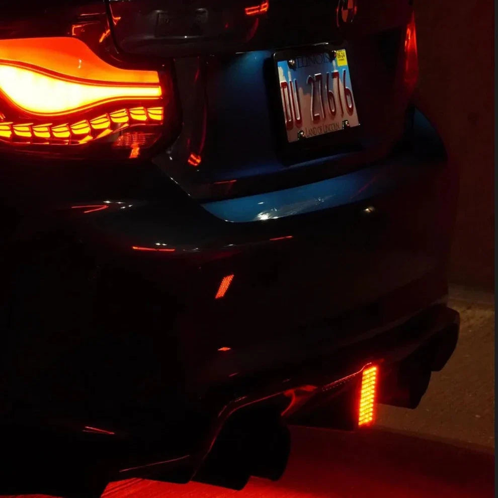 Rear of a blue BMW F87 M2 at night with red-lit one-piece LED Style carbon diffuser