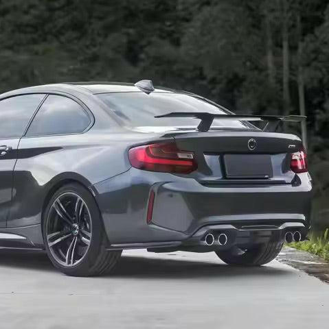 Szürke BMW F87 M2 hátulról ferdén GT szárnnyal, felszerelt íves carbon hátsó splitterekkel