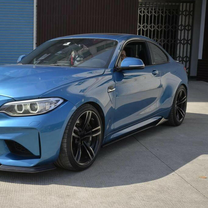 Blue BMW F87 M2, front-side view, with MTC Style carbon fiber side skirt extensions