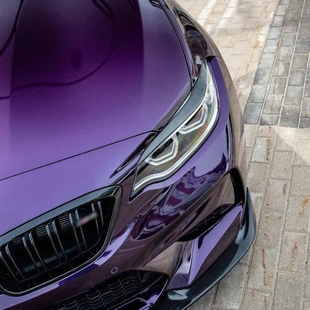 Headlight of a purple BMW F87 M2, close-up, with fitted carbon headlight eyelid