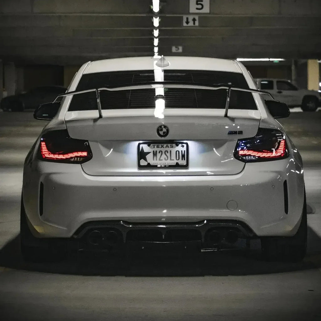 Fehér BMW F87 M2 hátulról parkolóban, világító GTS Style OLED hátsó lámpákkal