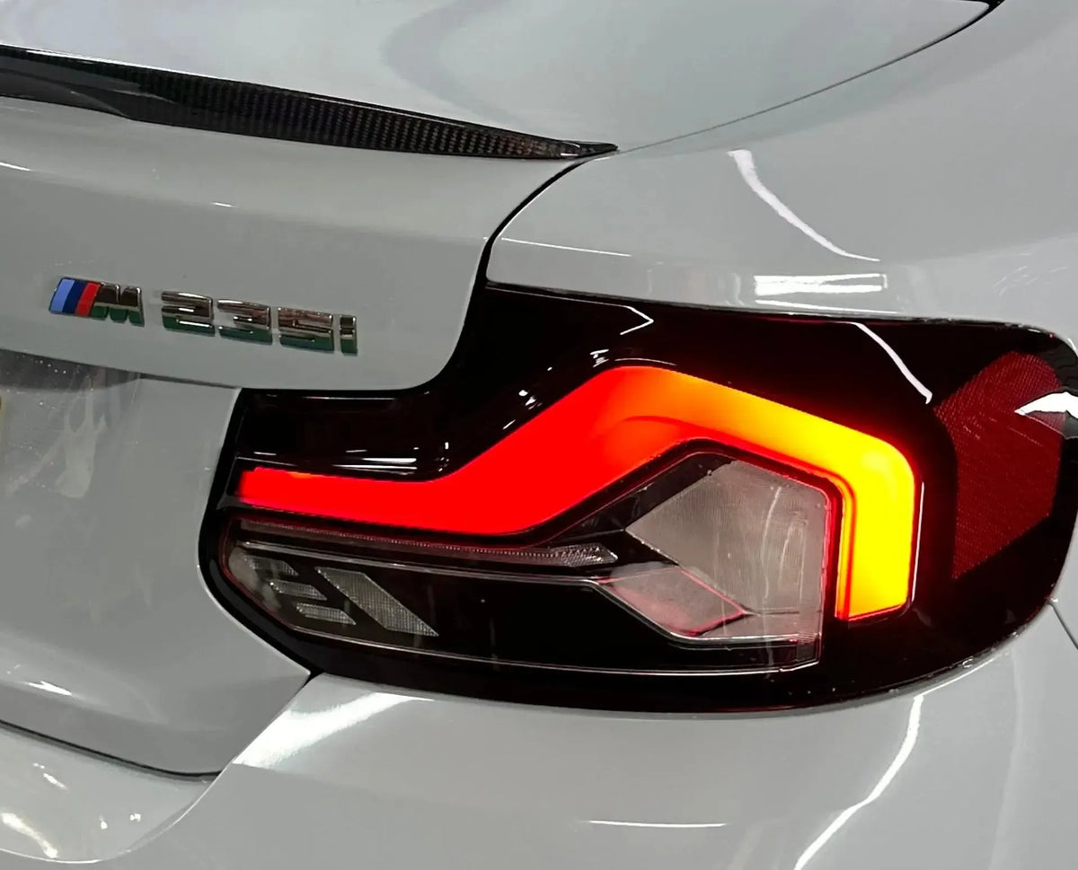 Illuminated LCI Style tail light of a white BMW 2 Series, close-up at an angle