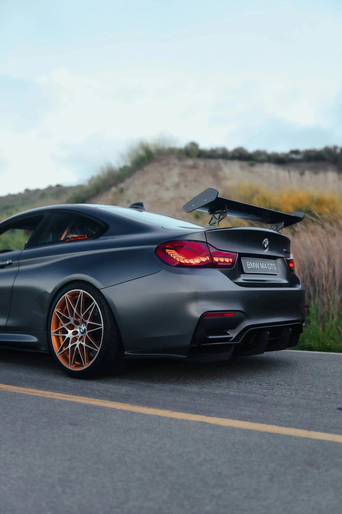 Szürke BMW F82 M4 GTS oldalról-hátulról, felszerelt GTS Style carbon hátsó szárnnyal