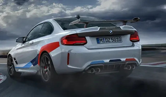 M csíkos fehér BMW F87 M2 Competition hátulról ferdén versenypályán, MP Style carbon szárnnyal