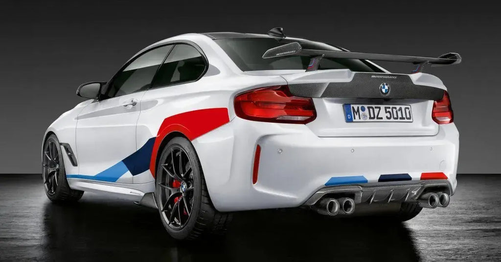 M csíkos fehér BMW F87 M2 Competition hátulról ferdén stúdióban, MP Style carbon hátsó szárnnyal