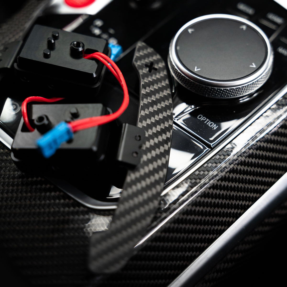 Carbon paddle shifter and magnetic switch modules on a BMW G Series center console, close-up