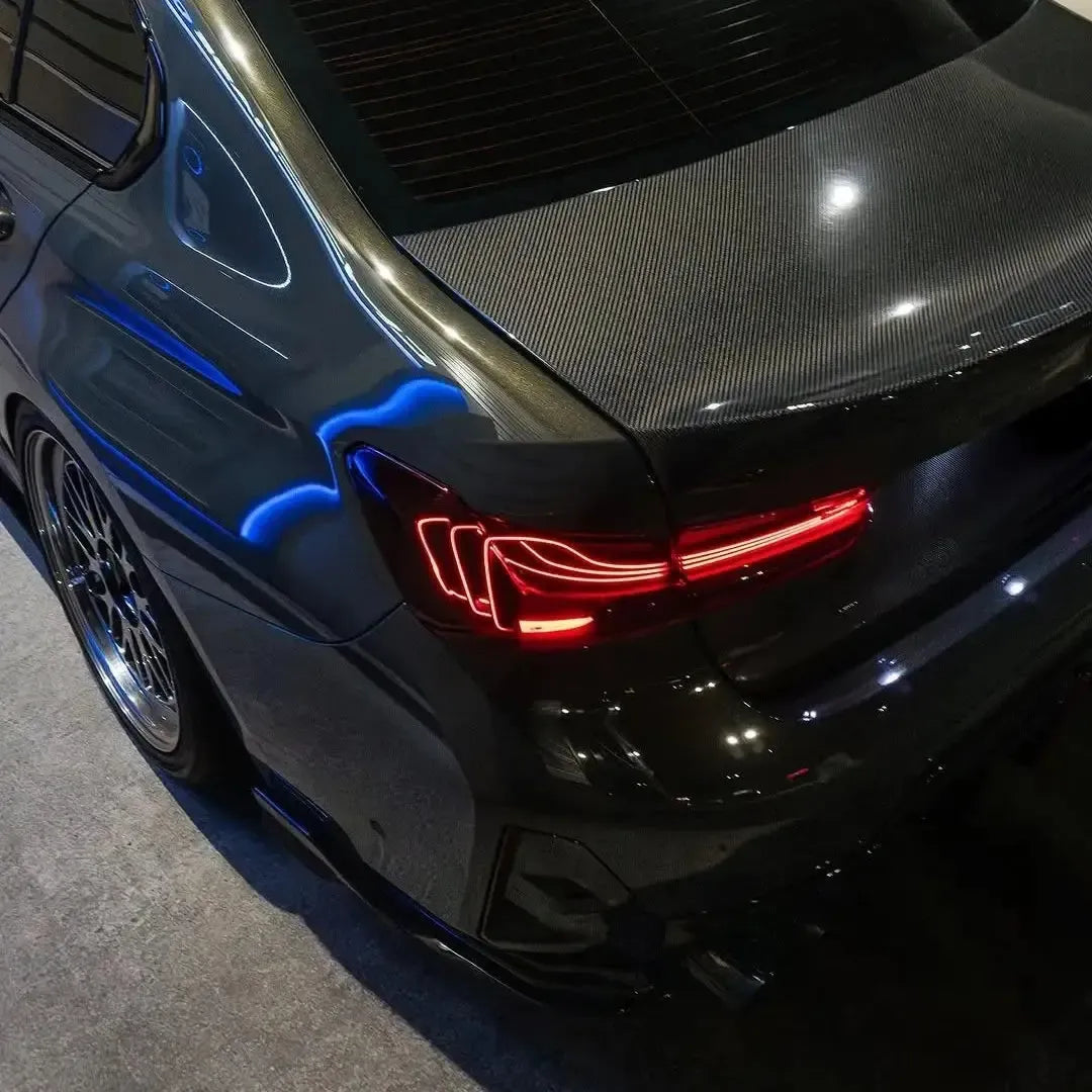 Close-up of a BMW G20 carbon trunk lid with ducktail, illuminated laser tail lights (CSL Style)
