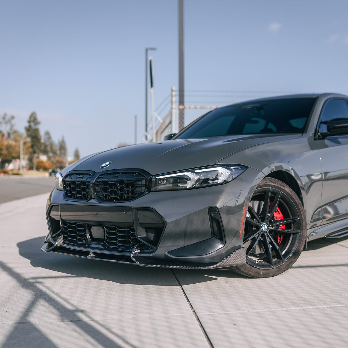 Gray BMW G20 LCI, left front three-quarter view, with fitted carbon fiber front lip (AD Style)
