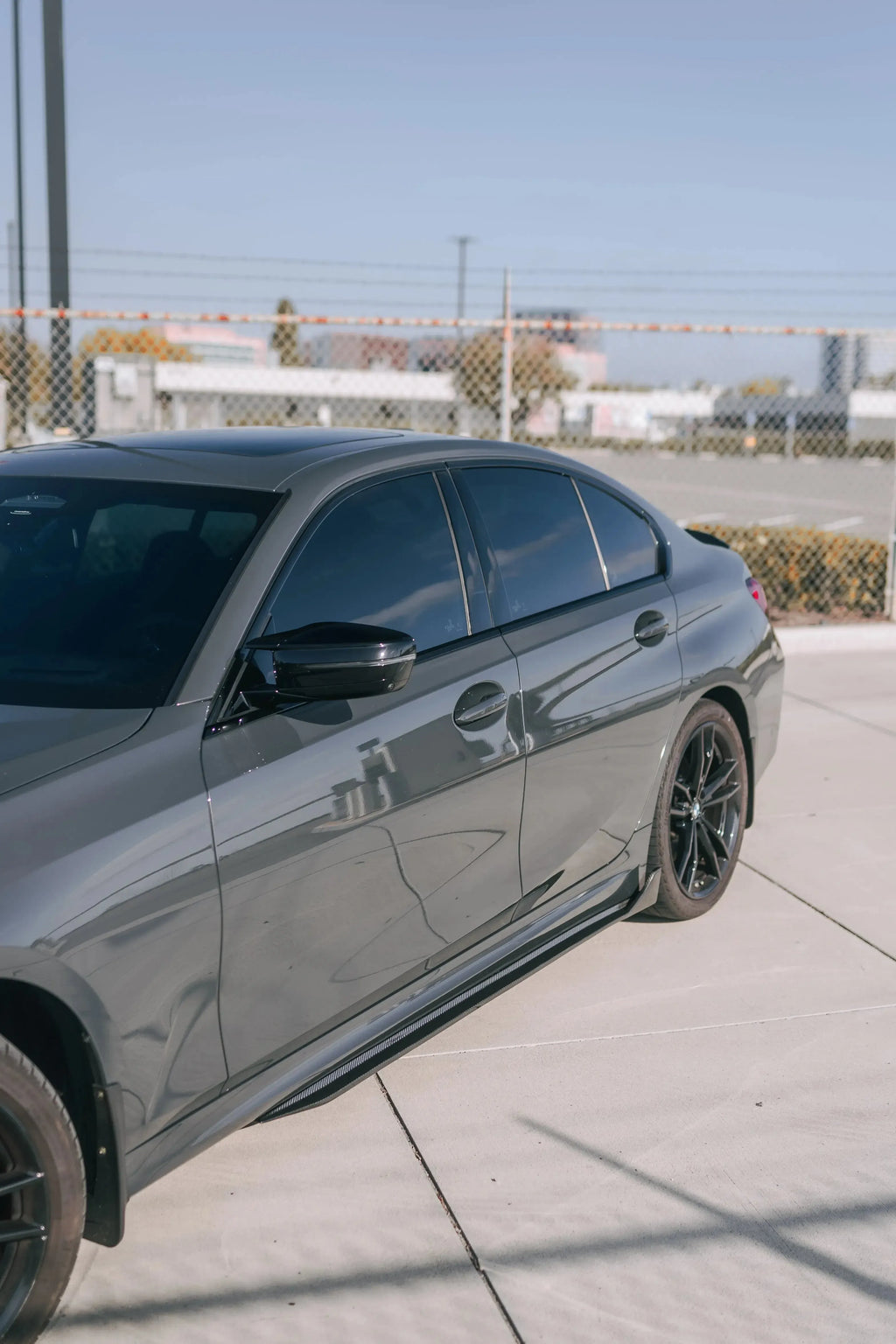 Gray BMW G20 in side three-quarter view, with carbon side skirts (TK Style)