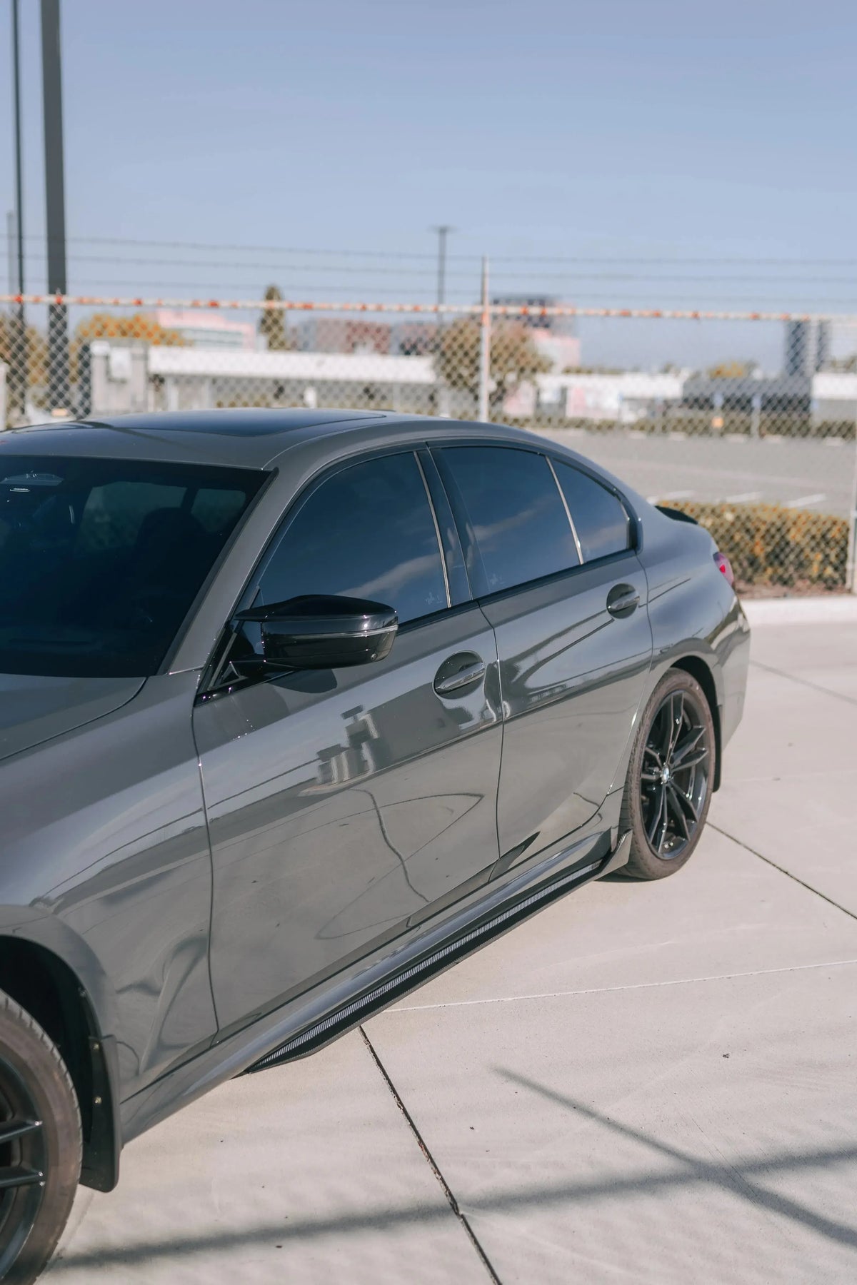 Gray BMW G20 in side three-quarter view, with carbon side skirts (TK Style)