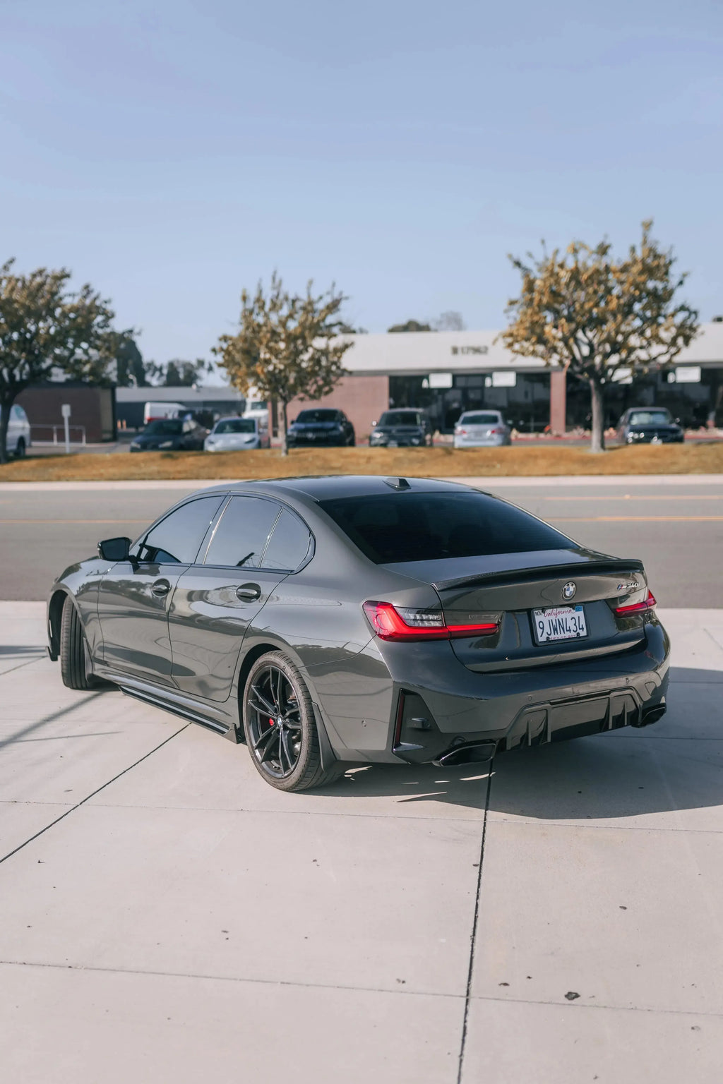 Gray BMW G20, rear three-quarter view: carbon side skirts and trunk spoiler (TK Style)