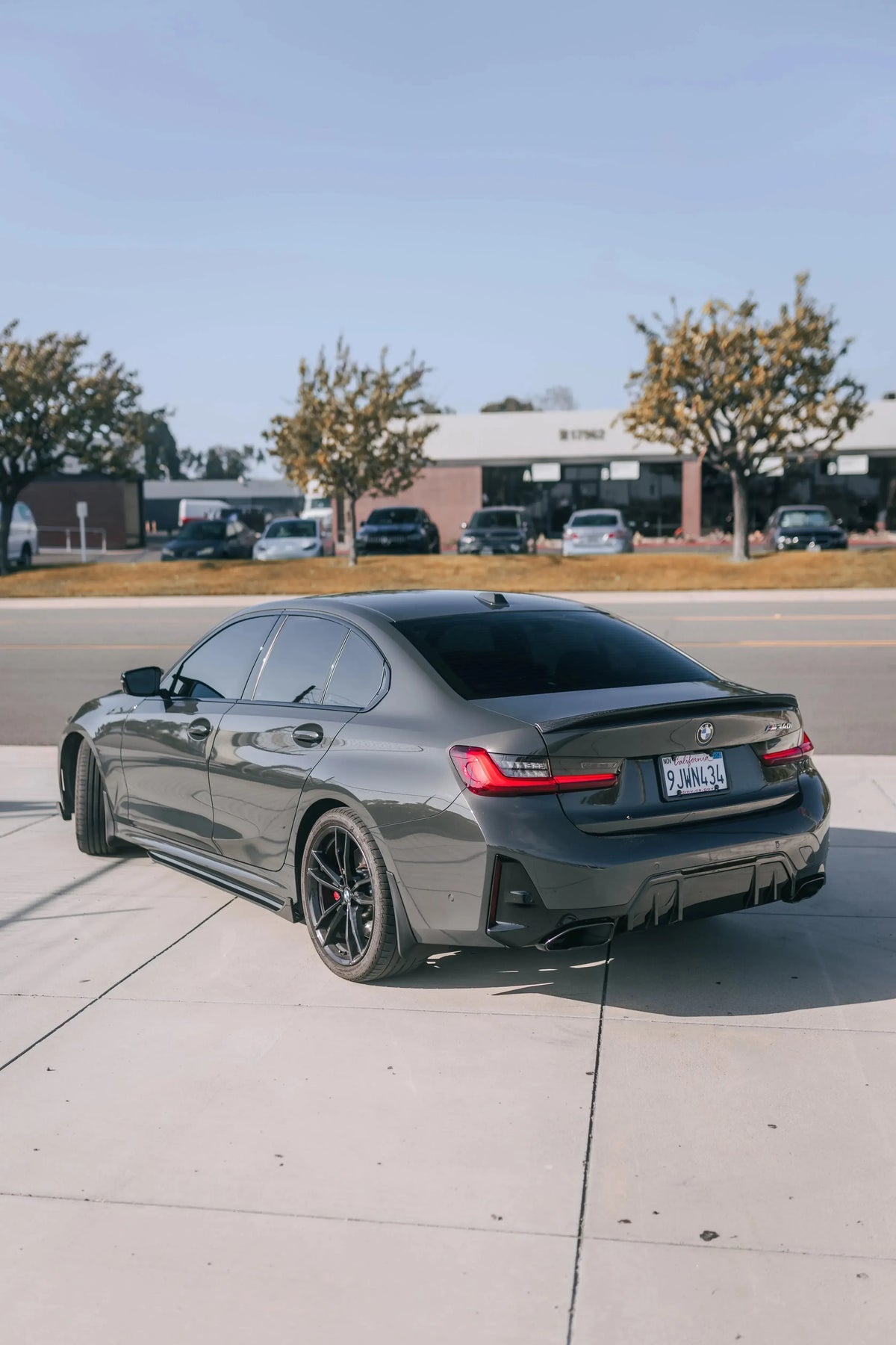 Gray BMW G20, rear three-quarter view: carbon side skirts and trunk spoiler (TK Style)