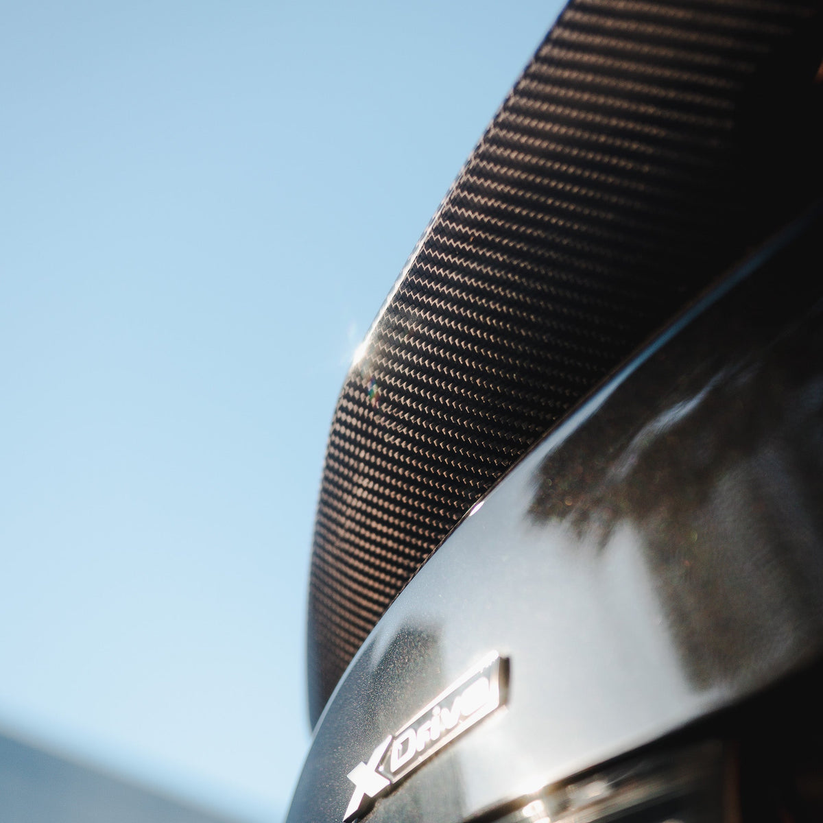 Close-up from below of the carbon spoiler on a black BMW G20 trunk (PSM Style High Kick)