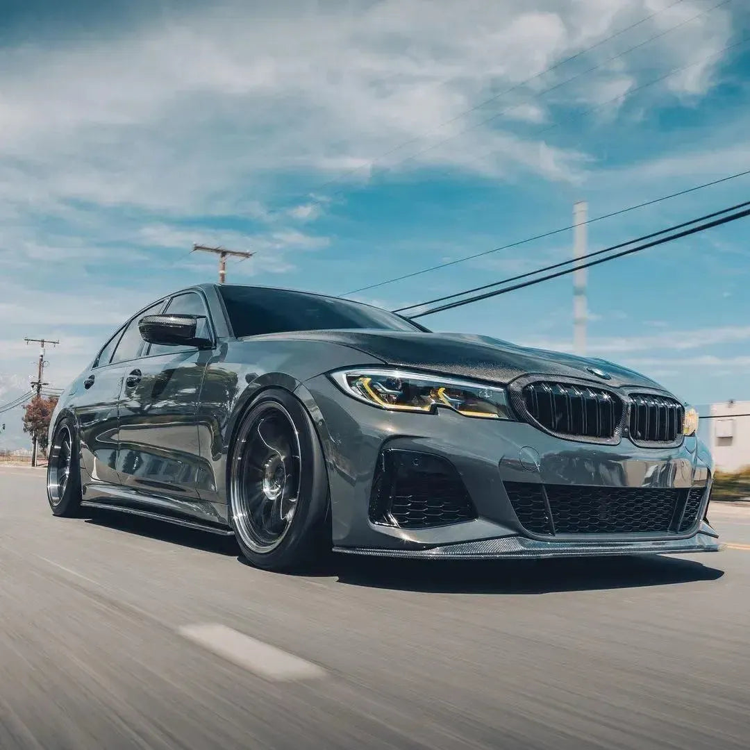 Gray pre-LCI BMW G20 on the move, front three-quarter view, headlights with yellow DRL (Laser Style)