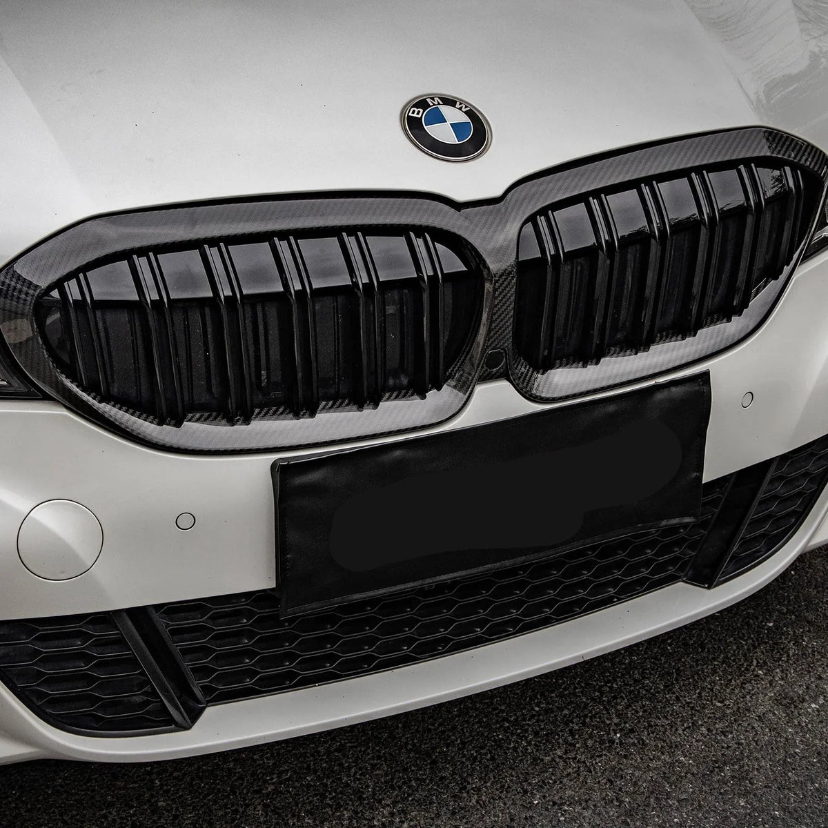 Close-up of a white BMW G20 front with fitted carbon-framed double-slat kidney grille