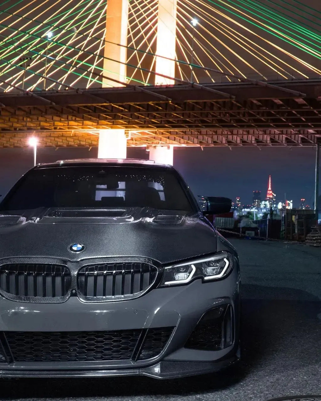 Gray BMW G20 from the front at night, with carbon-framed double-slat kidney grille and carbon hood