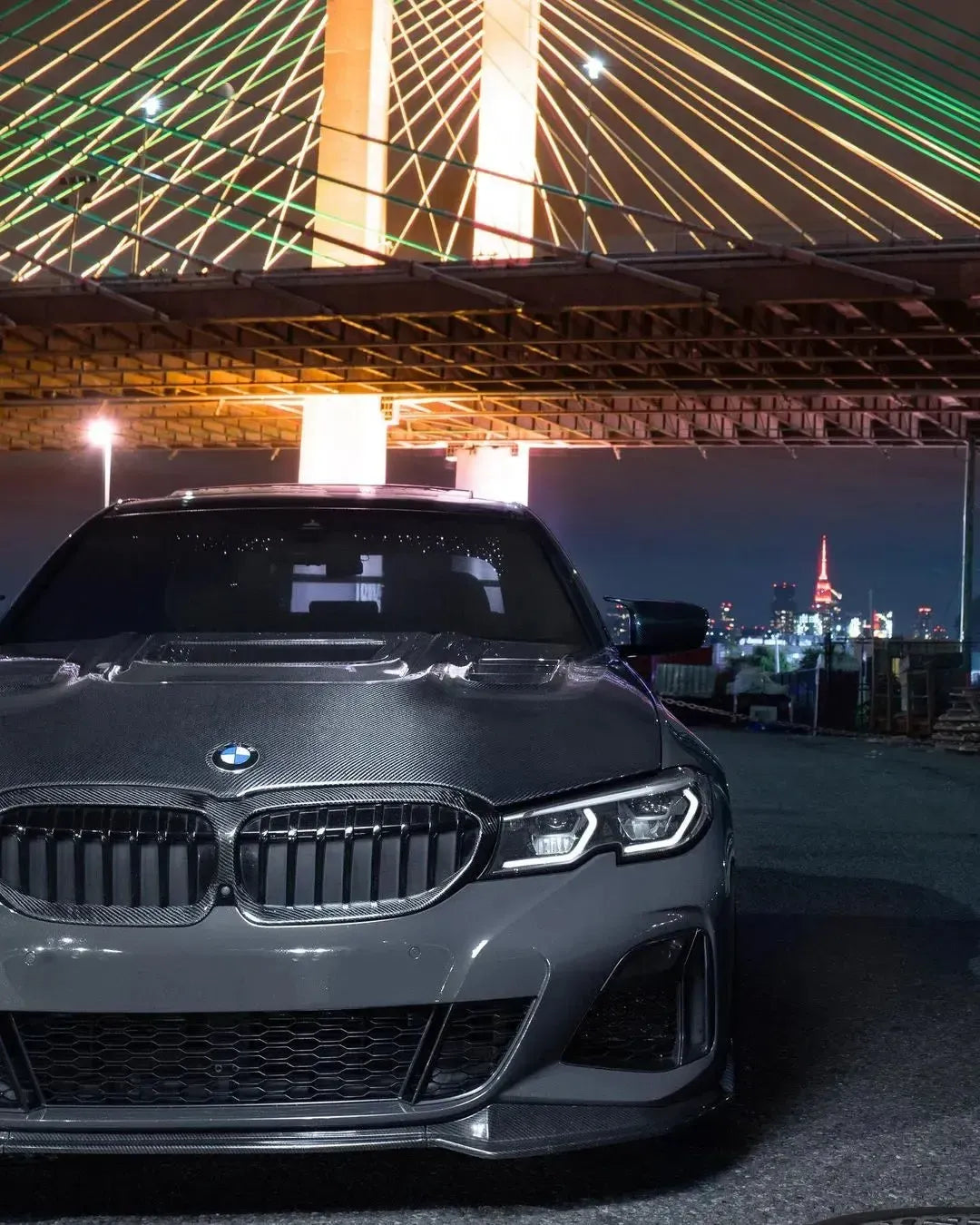 Gray BMW G20 from the front at night, with carbon-framed double-slat kidney grille and carbon hood