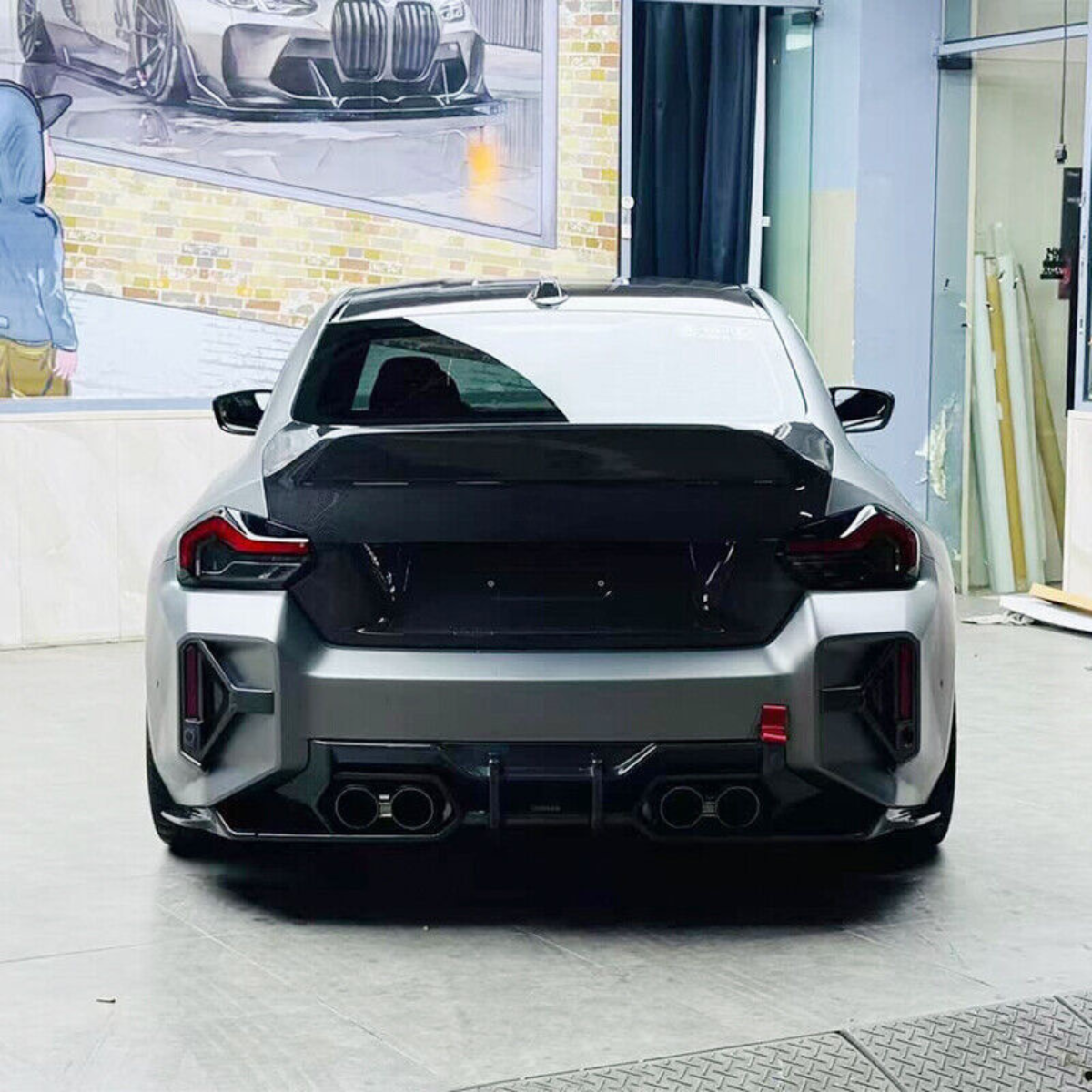 Gray BMW G87 M2 from behind in a workshop, with fitted CS Style ducktail carbon trunk lid