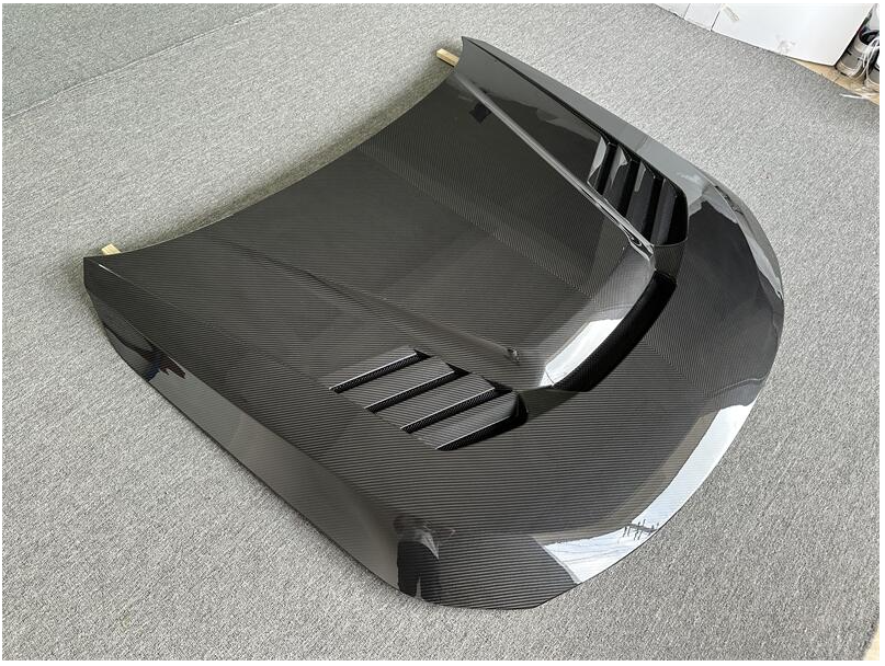 Szellőzős carbon fiber motorháztető elülső 3/4 nézetből, szürke háttéren (PM V1 Style) – BMW G87 M2