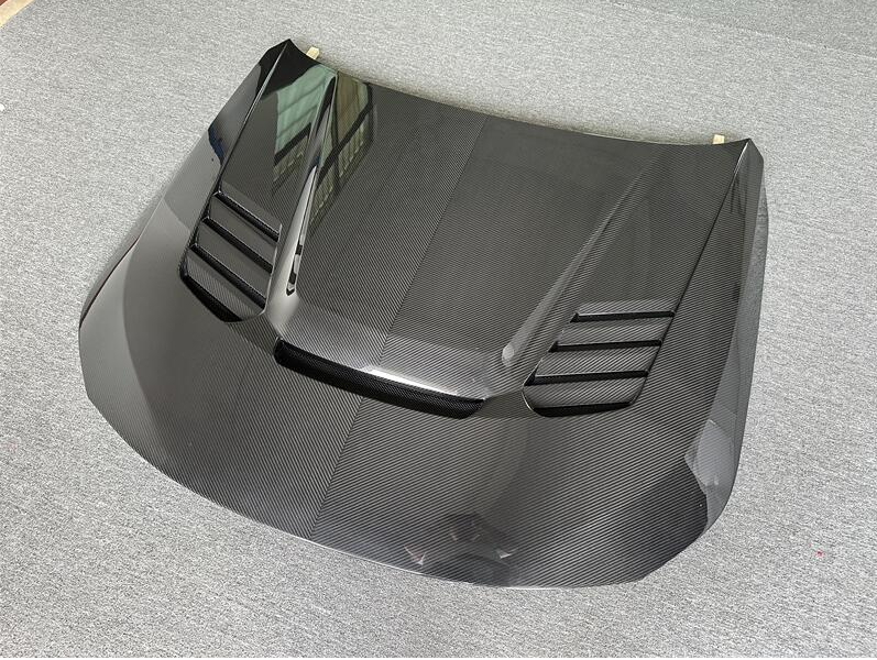 Szellőzős carbon fiber motorháztető hátsó 3/4 nézetből, szürke háttéren (PM V1 Style) – BMW G87 M2