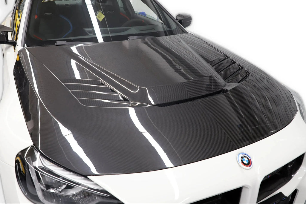Fehér BMW G87 M2 bal elülső 3/4 nézetből közelről, szellőzős V Style carbon motorháztetővel