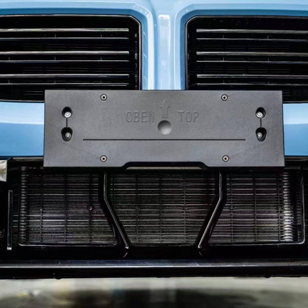Kék BMW G87 M2 alsó első lökhárítója közelről, a rendszámtartó mögé szerelt védőhálóval