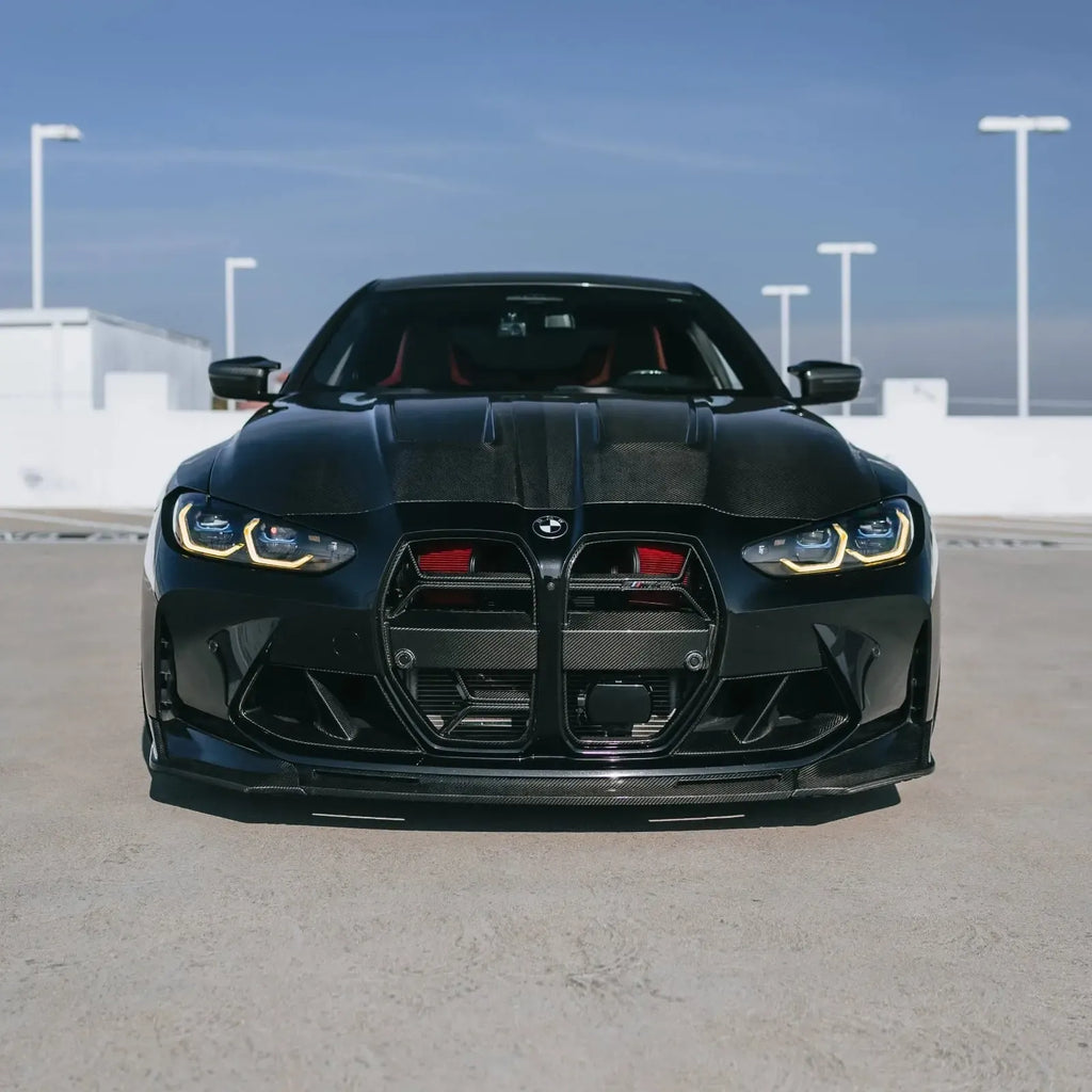 Black BMW G82 M4 from the front on a rooftop parking lot, with red Front mount intake filters behind the grille