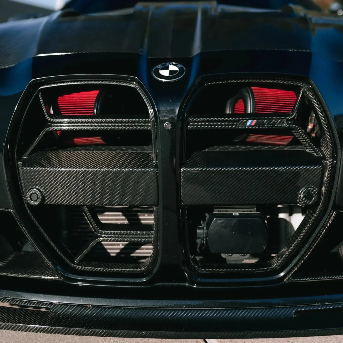 Kidney grille close-up, with red filters and carbon cover behind it (Front mount intake) – BMW G87 M2 / G80 M3 / G82 M4