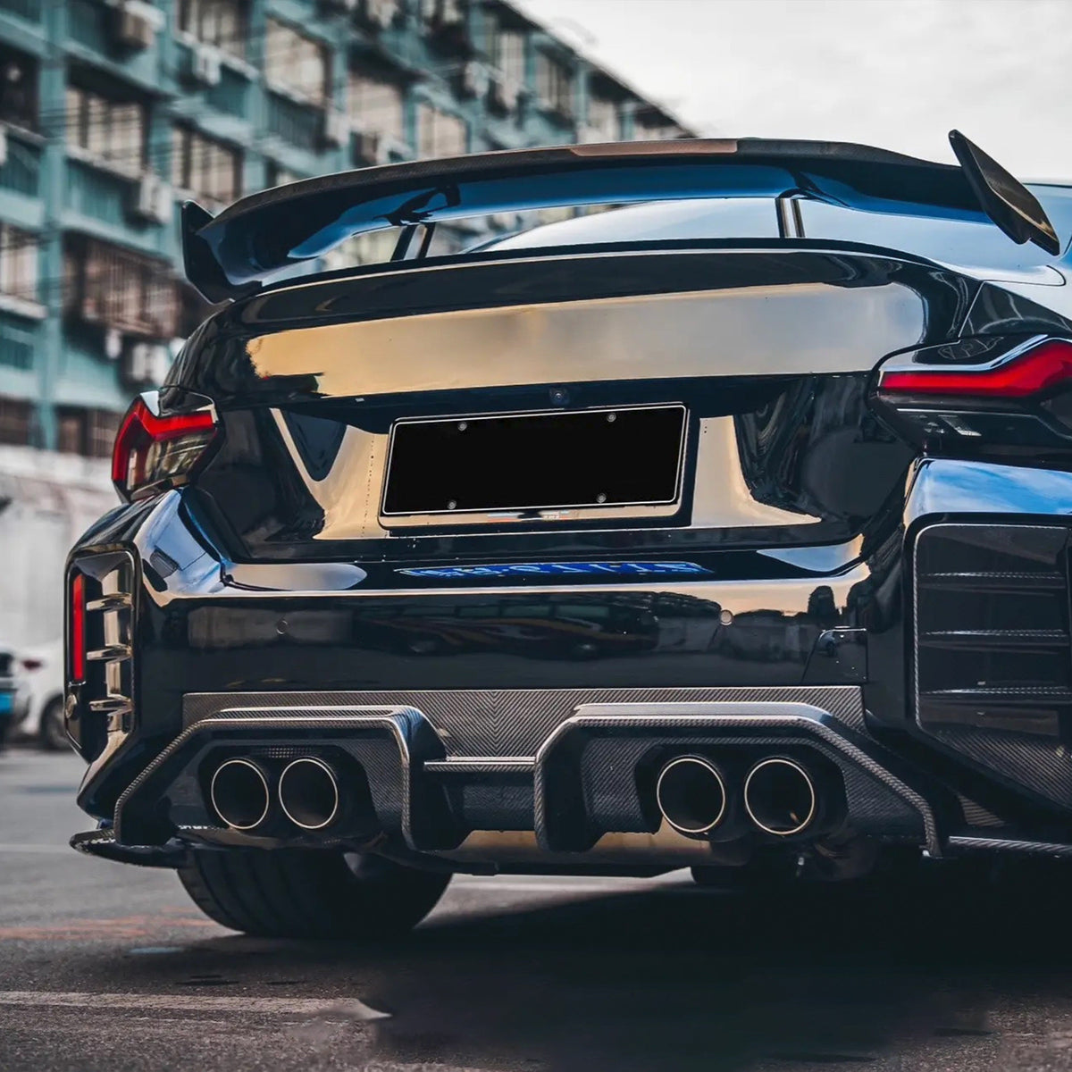 Rear of a dark BMW G87 M2 with carbon fiber rear diffuser (AD Style)