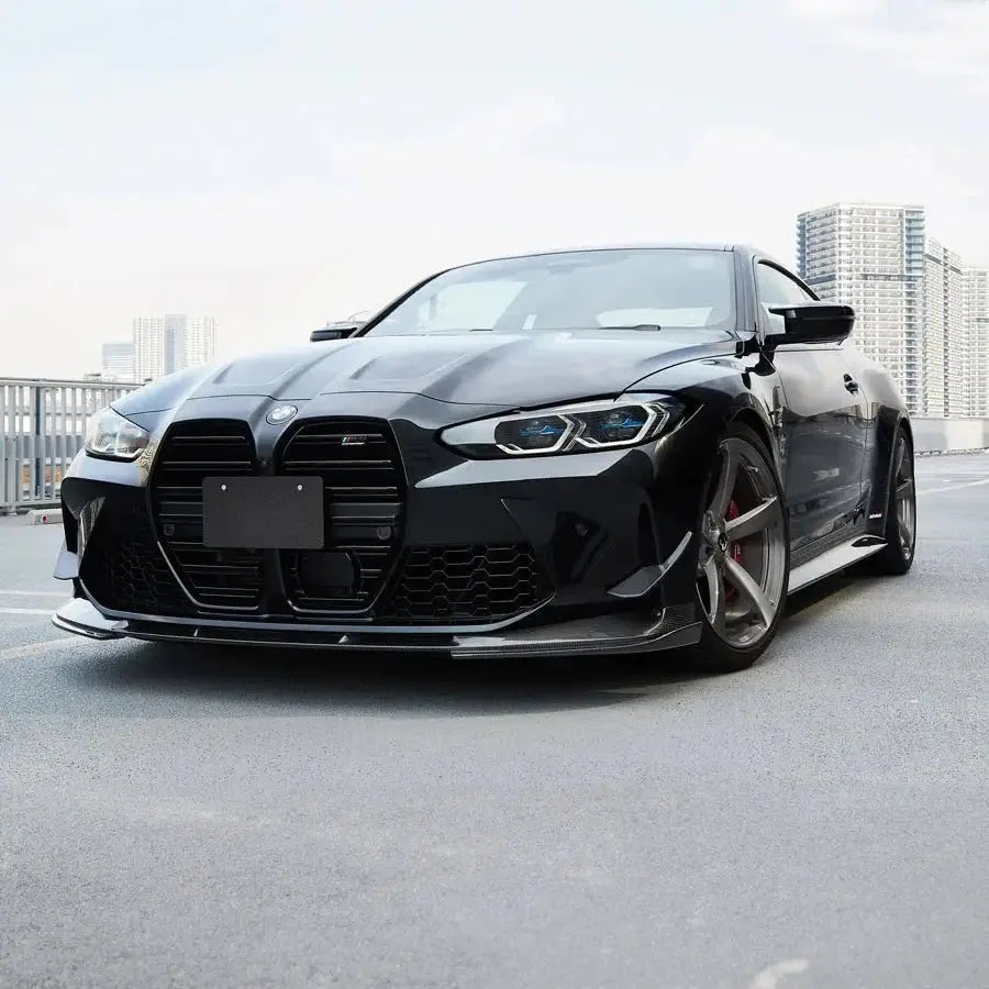 Fekete bmw m4 coupe első koptató karbon szálas anyagból sportos aerodinamikus kialakítással a kipufogó rendszerhez