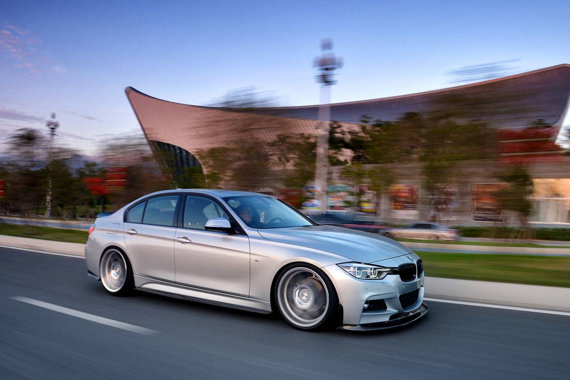 Ezüst BMW F30 haladás közben, oldalról-elölről fotózva, carbon első koptatóval (GV Style)