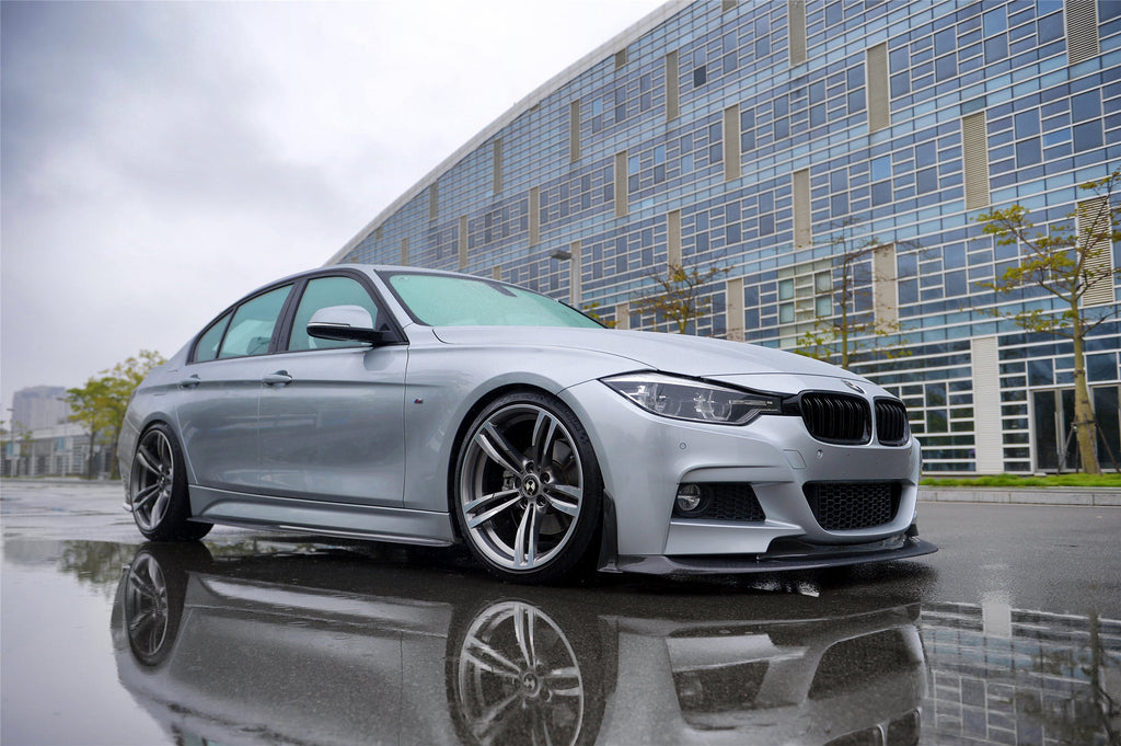 Ezüst BMW F30 alacsony első 3/4-es nézetből nedves aszfalton, carbon koptató szettel (GV Style)