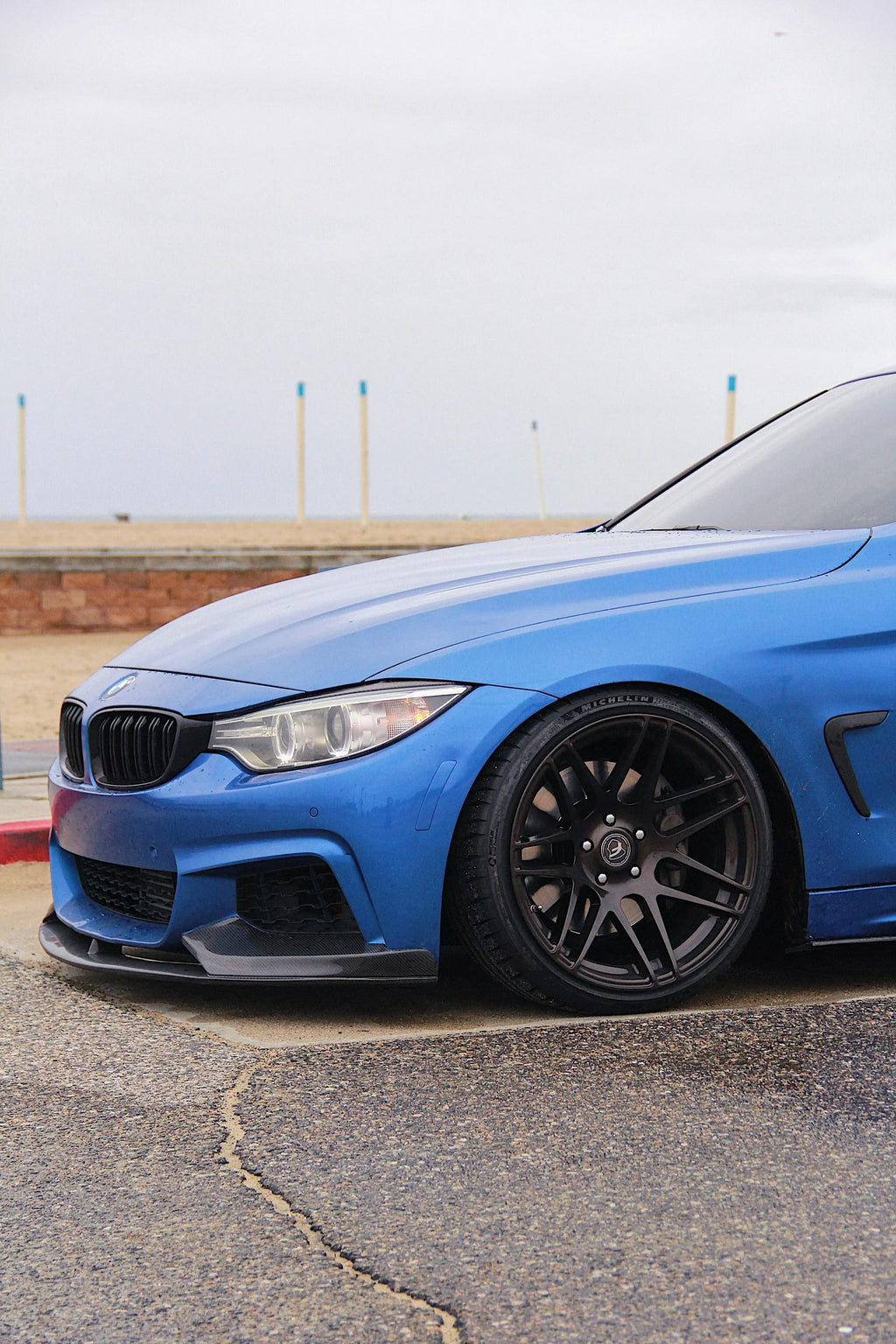 Kék BMW F32 coupé első háromnegyed nézetből, alacsony szögből, carbon első koptatóval (MP Style)
