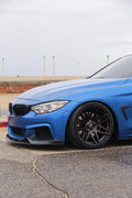 Kék BMW F32 coupé első háromnegyed nézetből, alacsony szögből, carbon első koptatóval (MP Style)