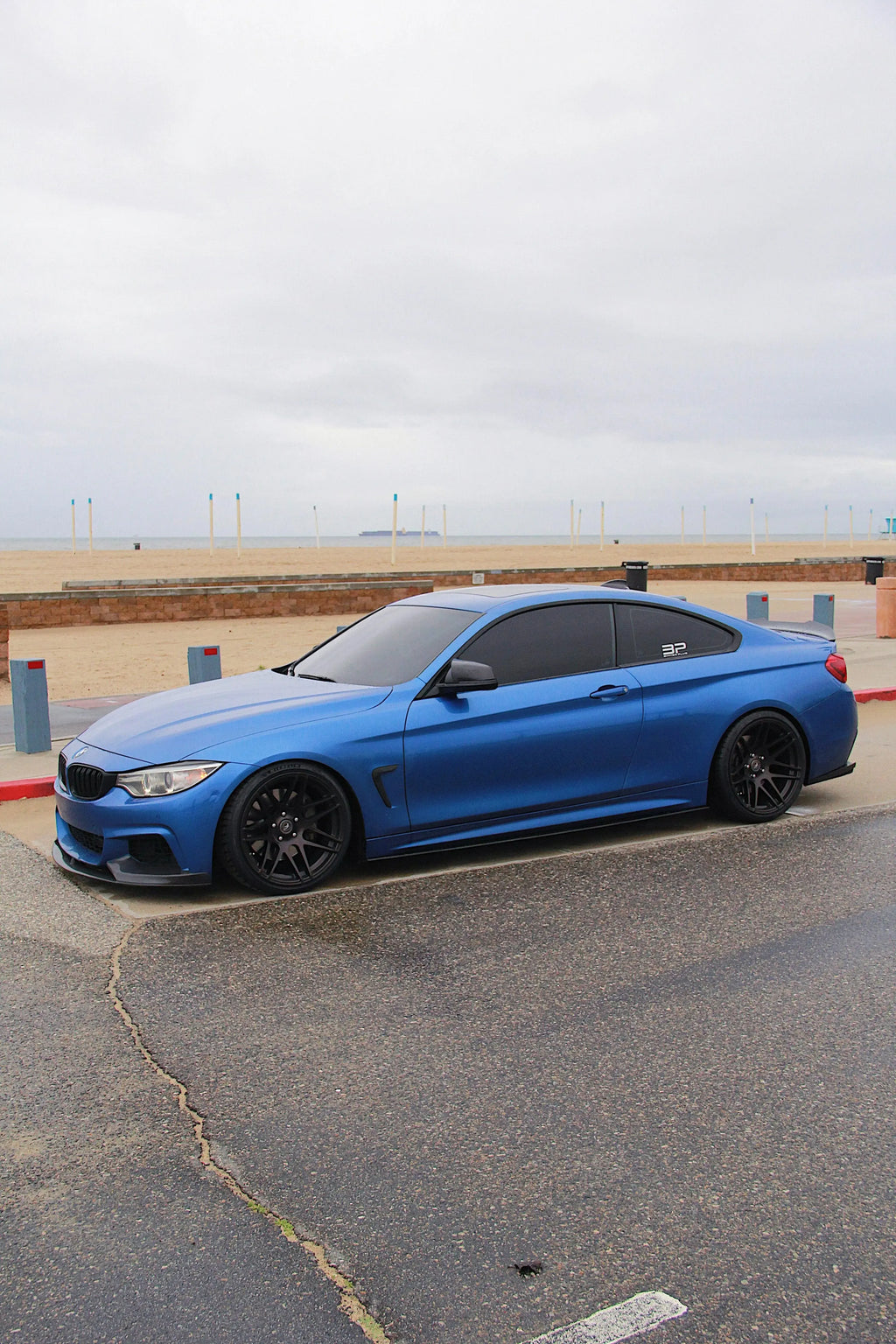 Kék BMW F32 coupé oldalsó háromnegyed nézetből a parkolóban, carbon első koptatóval (MP Style)