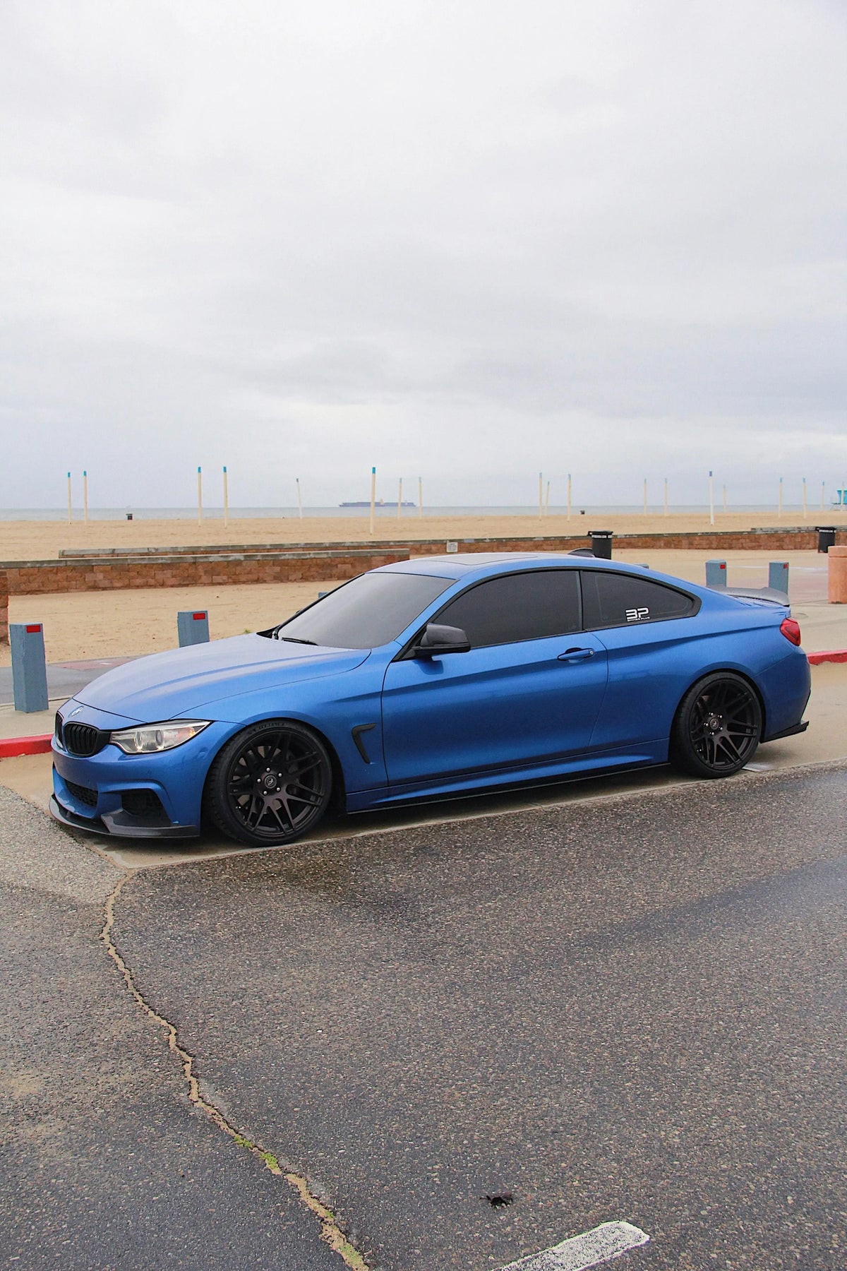 Kék BMW F32 coupé oldalsó háromnegyed nézetből a parkolóban, carbon első koptatóval (MP Style)