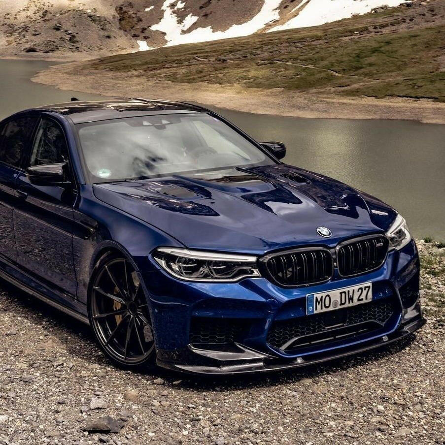 Blue pre-LCI BMW F90 M5 by a mountain lake, front three-quarter view, with carbon front lip (3D Style)