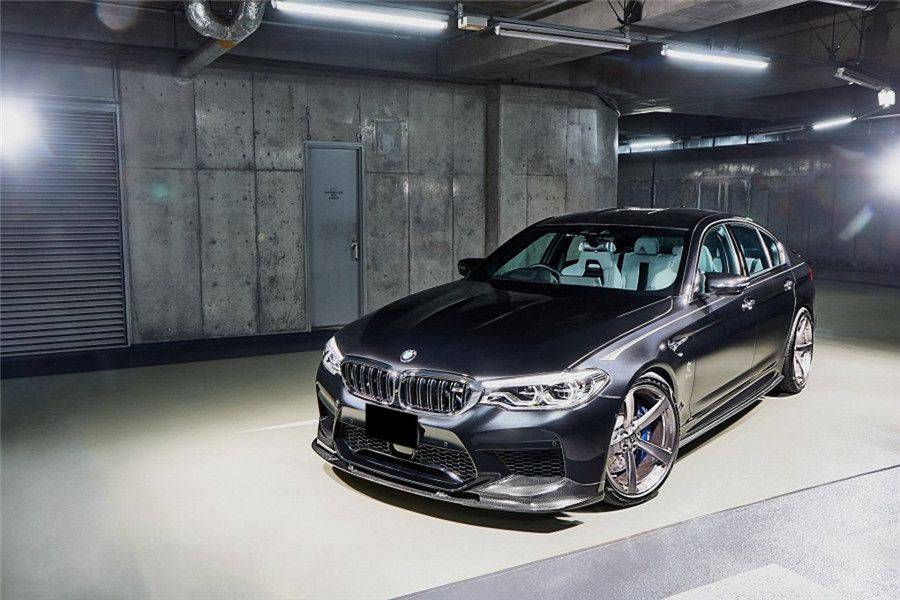 Dark gray pre-LCI BMW F90 M5 in a garage, front three-quarter shot with carbon front lip (D3 Style)