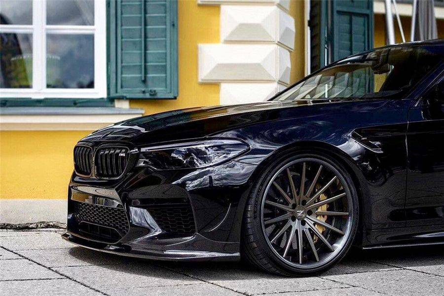 Close-up of a black pre-LCI BMW F90 M5 left front, with fitted carbon front lip (D3 Style)
