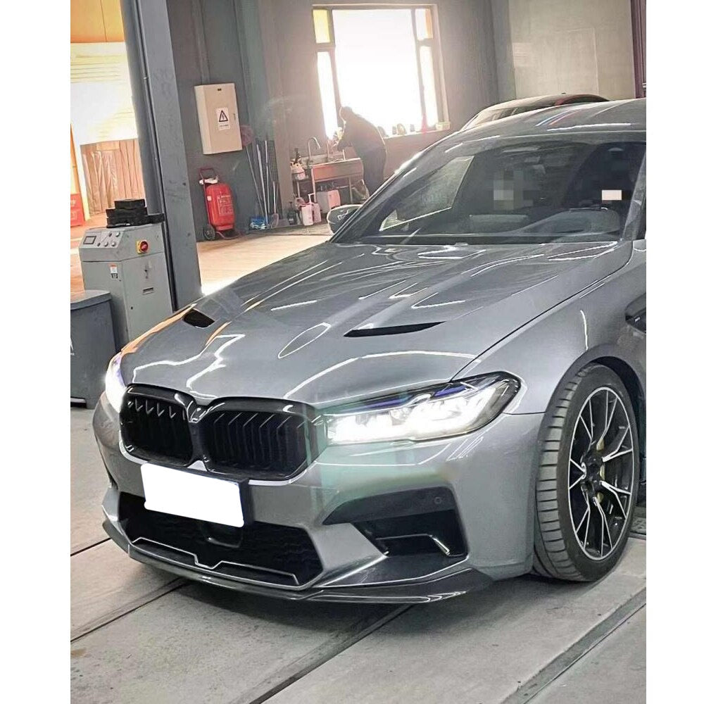 Gray BMW F90 M5 LCI in a workshop, with vented hood and carbon front lip (Slim Style)