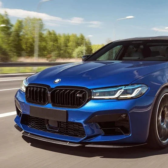 Blue BMW F90 M5 LCI while driving, front three-quarter view, with carbon front lip (ST Style)