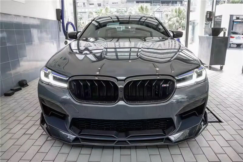 Gray BMW F90 M5 LCI head-on in a workshop, with carbon hood and front lip (Track Style)