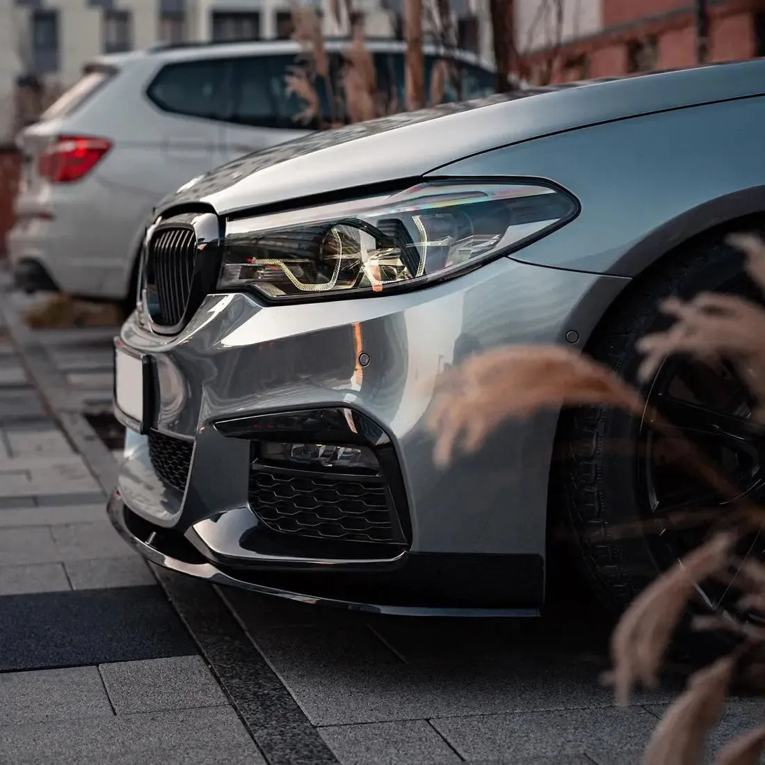 Close-up of a silver pre-LCI BMW G30 front corner, with fitted carbon front lip (MP Style)