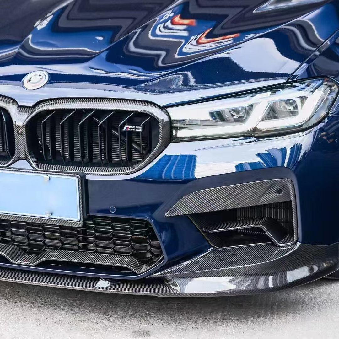 Kék BMW F90 M5 LCI eleje közelről, felszerelt carbon ködlámpa keretekkel (PM Style)