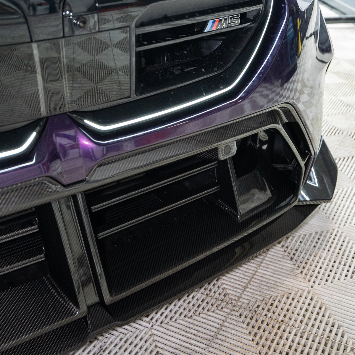 Lila BMW G90 M5 alsó eleje közelről, bordás carbon fiber középső díszléccel (SQ Style)