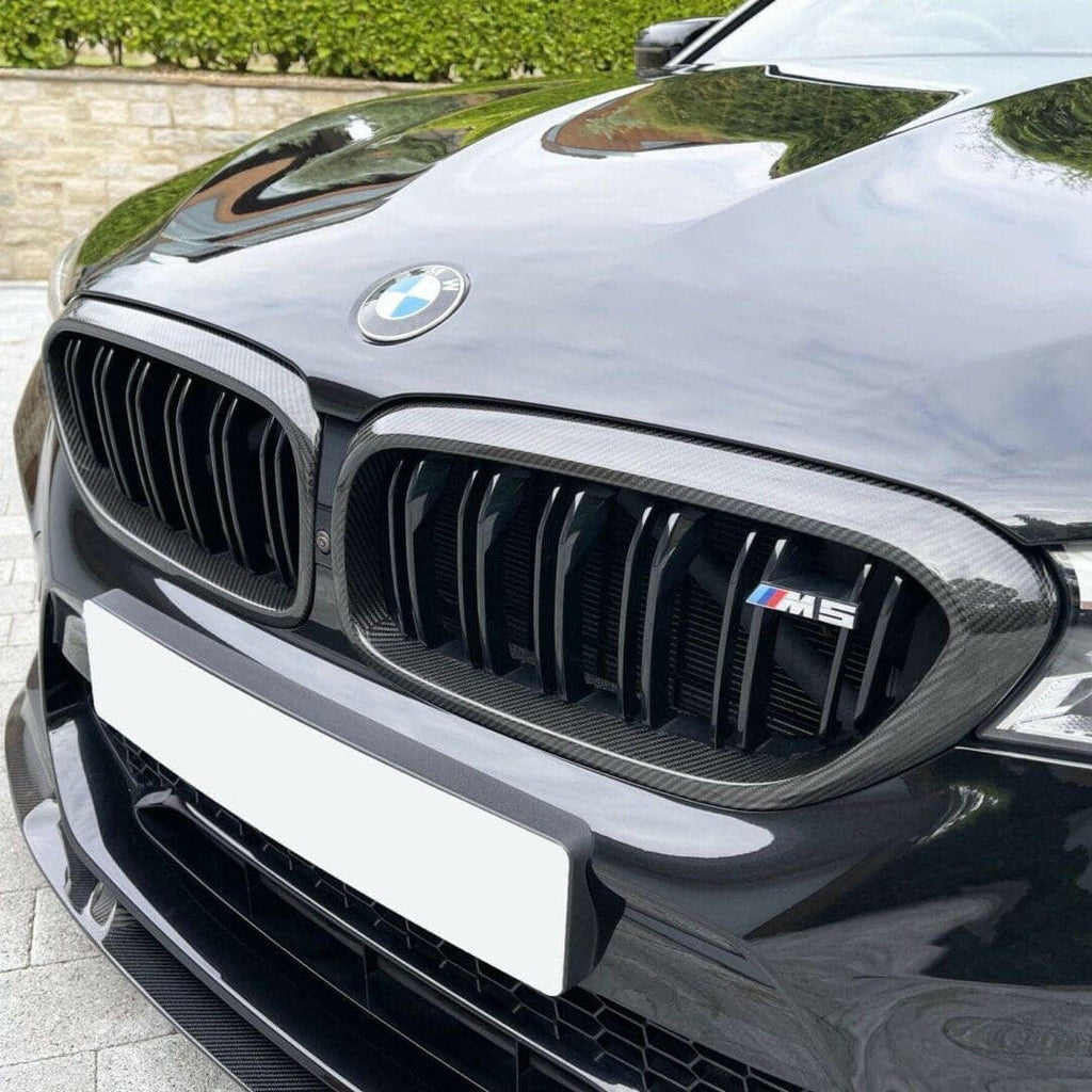 Fekete pre-LCI BMW F90 M5 orra közelről, dupla rácsos carbon vesével és M5 emblémával